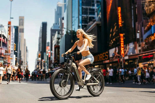 Shengmilo S700 white step-through fat tire electric bike ridden by a woman on busy downtown city street with skyscrapers.