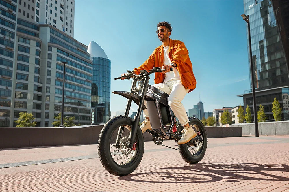 Shengmilo S900 full-suspension electric dirt bike ridden on a modern city plaza.